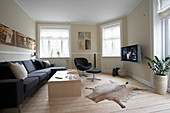 Dark grey sofa, armchair, TV, coffee table and animal-skin rug in living room