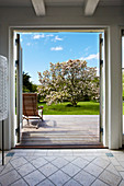 View through open door into sunny wooden terrace
