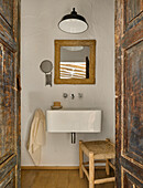 Blick durch geöffnete Holztüren auf Waschbecken im Badezimmer