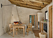 Essbereich vor gemauertem Kamin und Küchenzeile im Zimmer mit sandfarbenen Wänden und Schilfrohrdecke