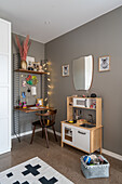 Regal mit integriertem Schreibtisch und Kinderküche im Zimmer mit grauen Wänden