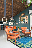 Armchairs with leather upholstery below gymnastic rings in living room with rustic wooden ceiling