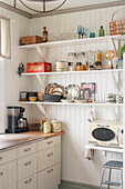 Open dish rack against white painted wooden wall in a kitchen