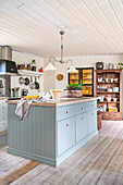 Light blue kitchen island in an eat-in kitchen with wooden floorboards