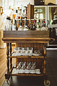 Rustikaler Getränkewagen mit Flaschen und Gläsern in einer Bar