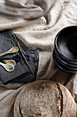Black dishes, black napkins and bread on a beige linen tablecloth
