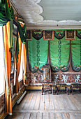 Antique chairs in a room with wooden floorboards and green wallpaper