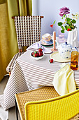 Table set for afternoon coffee with strawberries, flowers and striped tablecloth