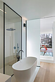 Glass partition between free-standing bath and shower area in bathroom