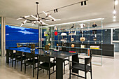 Dining area with black table and chairs and glass shelf as room divider in a luxury penthouse