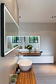 Wooden counter with a vessel sink, wall mirror above in the en-suite bathroom