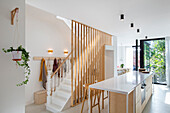 Kitchen island with white worktop and staircase with wooden slats