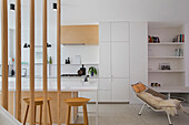 Offene Küche mit weißen Schränken und Kücheninsel, Klassiker-Liegestuhl im Wohnbereich