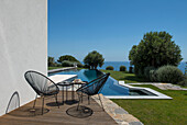 Terrasse mit Klassikersesseln, Blick auf Pool und Meer