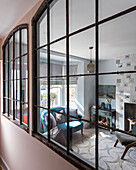 Large french metal salvaged windows with view through to sitting room, tiles around the fireplace, rug and sofa upholstered