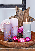 Verzierte Kerzen, Weihnachtskugeln und Holzstern in Holzschale