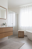 A washbasin, a shower area with a glass door and a freestanding bathtub in a bathroom