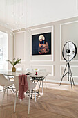 Dining room with designer furniture, floor lamp and artwork on wall with moulded panels