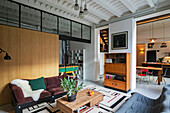 Sofas und Couchtisch vor Holzwand und Retro Highboard in einem Loft