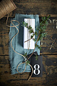 Making an Advent calendar: white-wrapped gift, juniper twig and black cardboard with number