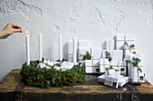 Weiß verpackte Geschenke als Adventskalender mit Wacholderwzeigen dekoriert und Adventskranz aus Wacholderzweigen
