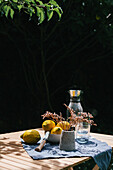 Zitronen und Wasserflasche auf Tisch im Garten