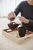Woman pouring tea on DIY tray with Viennese cane bottom