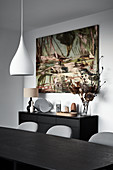View across dining table to modern artwork on wall above sideboard