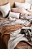 Double bed with pillows, brown bedspread and knitted blanket