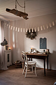 Old wooden table and chair below DIY bunting and wreath on wall