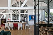 Esstisch aus Holz mit roten und weißen Stühlen, darüber Kronleuchter in offenem Wohnraum