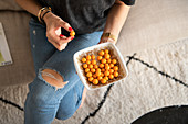 Woman's hand holds bowl of Cape gooseberries