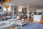 Open living room in maritime nautical style with kitchen island, dining table, and sofa