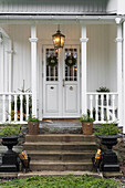 White wooden house with covered front porch decorated for Christmas