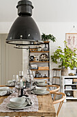 Set dining table with rustic table top, above it industrial lamps