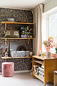 Shelves with throw pillows and vintage decoration on wall with wallpaper