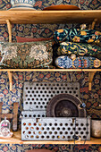 Shelves with cushions and vintage decoration on wall with wallpaper