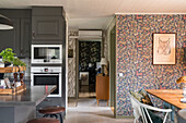 Open kitchen with built-in appliances and dining area, wallpaper with jungle design on the wall