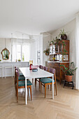 Weißer Tisch mit gepolsterten Stühlen und antike Anrichte in renovierter Wohnküche