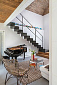 Piano under metal stairs in a living room with cathedral ceiling