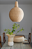 Dining table with old wooden top, woven wicker lamp above it