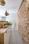 Schmale Küche mit Natursteinwand in offenem Raum