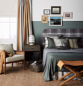 Double bed with a flannel headboard, bedside table, armchair, and leather stool in bedroom