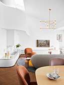 Hoher Wohnraum mit weißer, gebogener Wand und eleganten Polstermöbeln