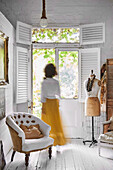 Woman goes to patio door of shabby chic living room