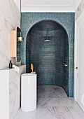 Shower area with round arch and turquoise blue wall tiles in elegant bathroom with marble