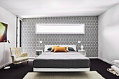 Floating bed and armchair in bedroom with trellis wallpaper