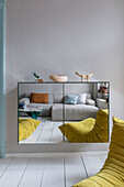 Floating cabinet with mirrored doors showing reflection of sofa and designer armchair
