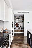 Shaker-style cupboards in open kitchen with view into pantry
