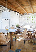 Frühstückstisch mit Stühlen, im Hintergrund Sofa mit Kissen im Zimmer mit weiß getünchter Ziegelwand